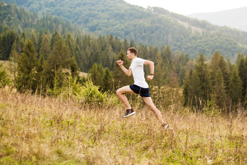 Obraz premium Running fitness man sprinting outdoors with beautiful mountains landscape on background. Caucasian sport male runner training for marathon.