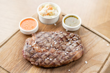 Sliced medium rare grilled Steak Ribeye with Pickled cabbage and two sauces. Serving on a wooden Board. Barbecue restaurant menu, a series of photos of different meats.
