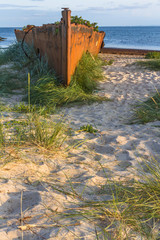 Naklejka premium An old rusty and damaged batteship wreck on the beach. Hel, Poland