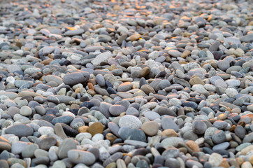 Large pebbles on the beach, with glare of the red sun