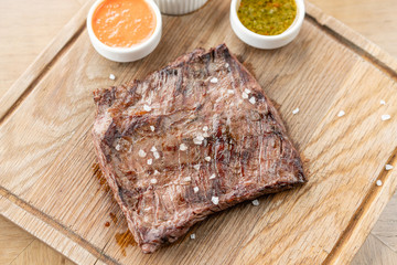 Grilled Skirt Steak with Pickled cabbage and two sauces. Serving on a wooden Board. Barbecue restaurant menu, a series of photos of different meats.