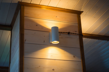 Glowing warm light lamp on a wooden wall in the interior