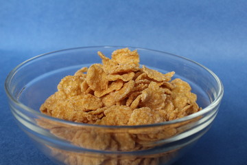cornflakes in bowl plate on blue background