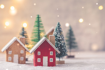 Miniature wooden houses on the snow over blurred Christmas decoration background, toned, postcard...