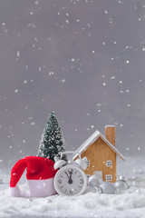 Naklejka premium Christmas alarm clock, Santa Claus hat, small wooden toy cottage and fir-tree with balls, New Year postcard concept