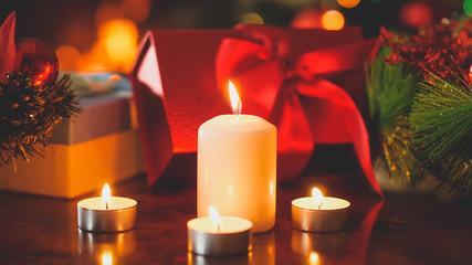 Closeup toned image of burning candles against lots of colorful boxes with Christmas gifts and presents