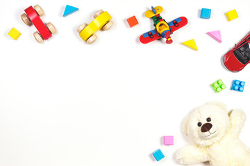 Baby kids toys frame with toy cars, teddy bear, colorful plane, wooden bricks on white background. Top view, flat lay