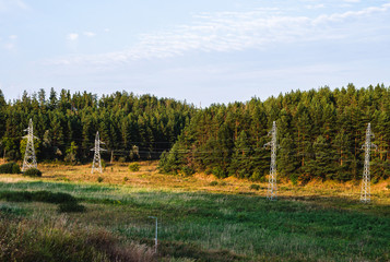 Fototapeta na wymiar Power line with metal supports on forest background