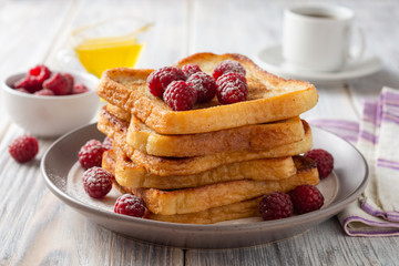 French toasts with powdered sugar and fresh raspberries on wooden table. Selective focus.