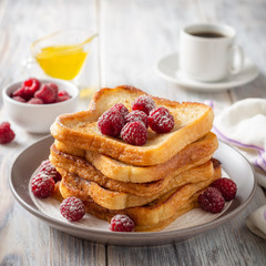 French toasts with powdered sugar and fresh raspberries on wooden table. Selective focus.