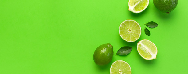 Fresh juicy lime and green leaves on bright green background. Top view flat lay copy space....