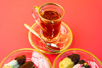 tea with saffron, sweet dates on crystal plates, golden design, chocolate bites, vivid background