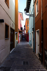 Fototapeta na wymiar Narrow passage between colorful old buildings in city center. Caorle Italy