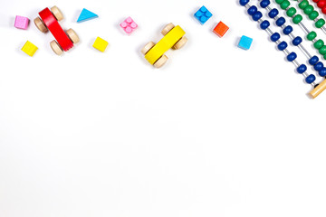 Baby kids toys frame with toy abacus, wooden cars and bricks on white background. Top view, flat lay. Copy space for text