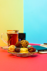 saffron tea, sweets on a plate, mobile phone, lens, teacup, golden design