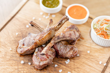 Rack of lamb , grilled meat with bone with Pickled cabbage and two sauces. Serving on a wooden Board. Barbecue restaurant menu, a series of photos of different meats.