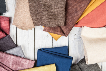 Arrangement from various colorful textile materials on white wooden background