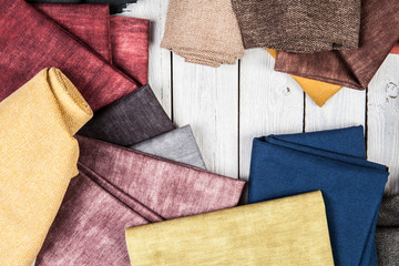 Arrangement from various colorful textile materials on white wooden background
