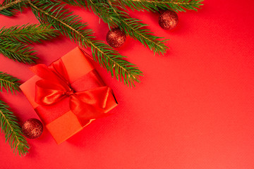 Christmas composition. Red gift, branches of spruce, red decorations on a red background. Christmas, winter, new year concept. Flat lay, top view, copy space