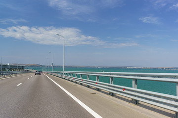 Crimean bridge across the Kerch Strait. Descent from the height of the navigable arch span. Ahead of Kerch and the sea is calm. Sunny day