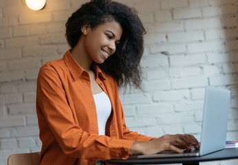 Portrait of young successful copywriter working freelance project remotely. Cheerful African...