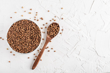 buckwheat in a white plate on a white background top view wooden spoon