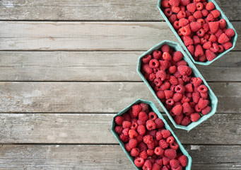 Fresh red raspberries in craft stalls, containers. on a wooden rustic old background. Top view of ripe berries. Autumn harvest.