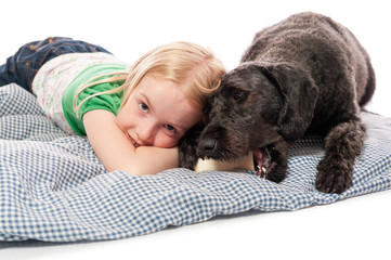 Little girl cuddling a labradoodle chewing on a bone. Isolated on white studio background