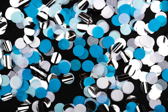 Silver, Blue And White Confetti On Black Background. Flat Lay, Top View.