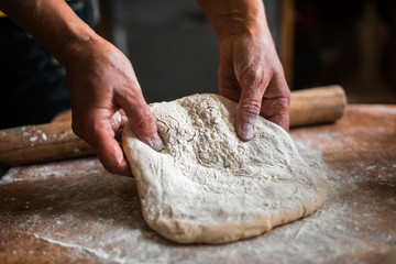 Making dough by female hands on wooden table background close up