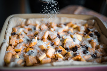 woman cooking apple pie. sprinkle apples with sugar. close-up. delicious pie made at home