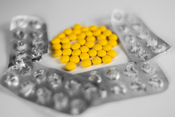 yellow pills on a white background. around lies used packaging