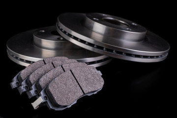 Steel brake discs and brake pads for a passenger car. New spare parts for car repairs.