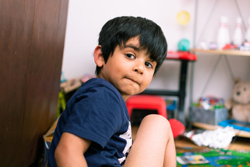 4-5 years indian kid, closeup portrait,  playing with his toys in playroom
