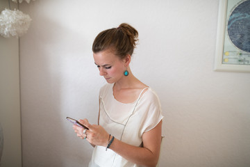 Fototapeta premium Woman looking seriously at her cell phone in front of a white wall
