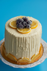  Front close-up of a cream cheese, lemon and blueberry cream cake. Blue background.