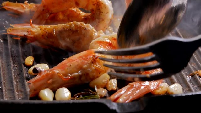 Close up fresh prawn been grilled in metal pan with garlic and rosemary.