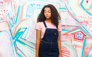young pretty african american woman feeling sad, upset or angry and looking to the side with a...