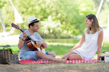 young man sitting on picnic blanket with his girlfriend
