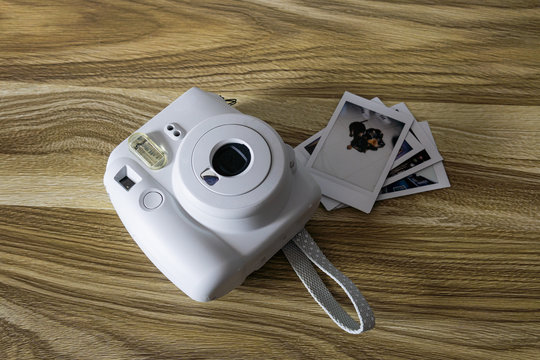 camara instantanea blanca con foto de perro  sobre madera