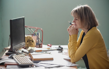 Adult teacher of college technical discipline sitting by her desk.
