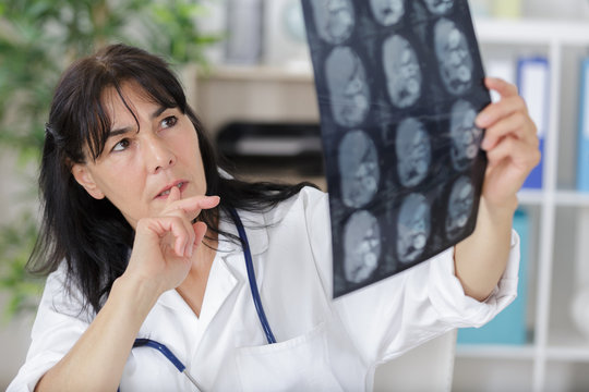 female doctor in doctors room looking at x-ray image