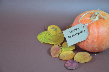 Thanksgiving Day. Pumpkin, pumpkin with autumn leaves and apples. Autumn harvest on a brown background. Happy Thanksgiving Lettering set table for celebration. fork and knife