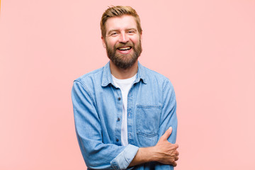young blonde adult man laughing shyly and cheerfully, with a friendly and positive but insecure...