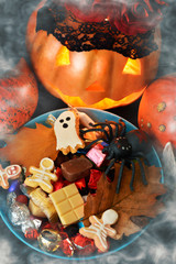 Halloween pumpkin with wreath of red roses on the head and candy bowl spider.	