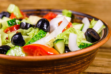 Ceramic plate with greek salad on wooden table
