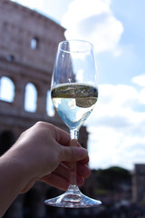 Woman's hand takes glass of champagne on the background of the Colosseum. Christmas concept. Christmas and New Year in Italy