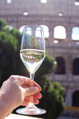 Woman's hand takes glass of champagne on the background of the Colosseum. Christmas concept. Christmas and New Year in Italy