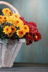 Autumn background with beautiful flowers in basket on the table.