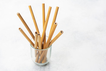 Stack of eco friendly biodegradable bamboo straws on white table, selective focus